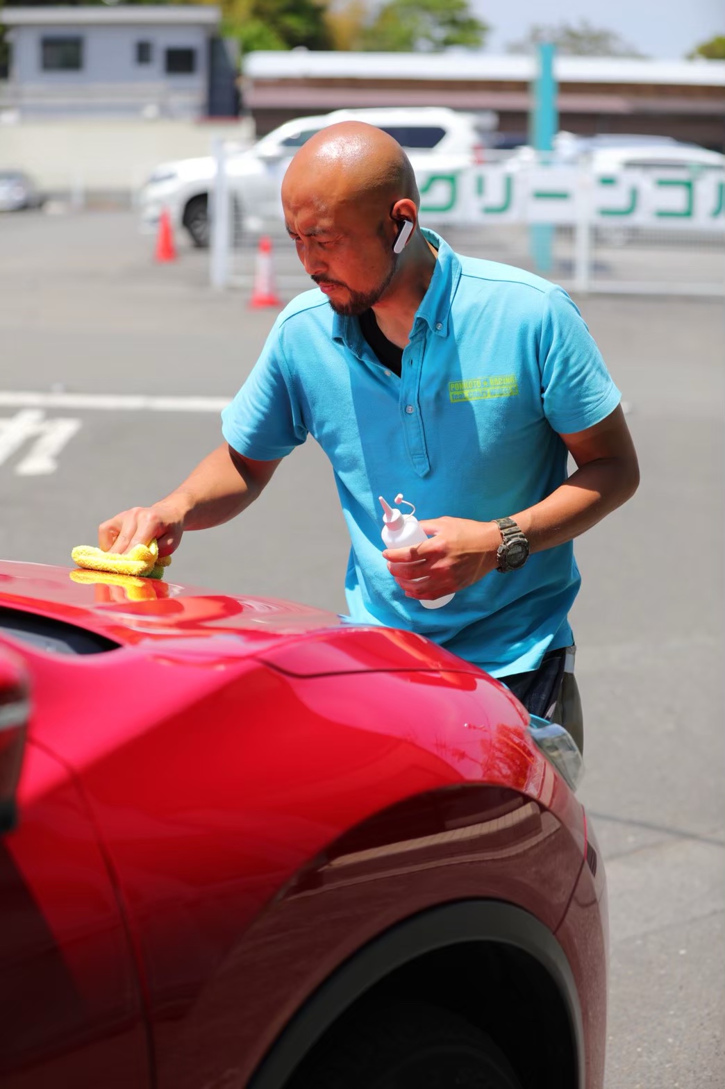 赤い車を丁寧に手入れするPONKOTU★MAN代表のぴーまん